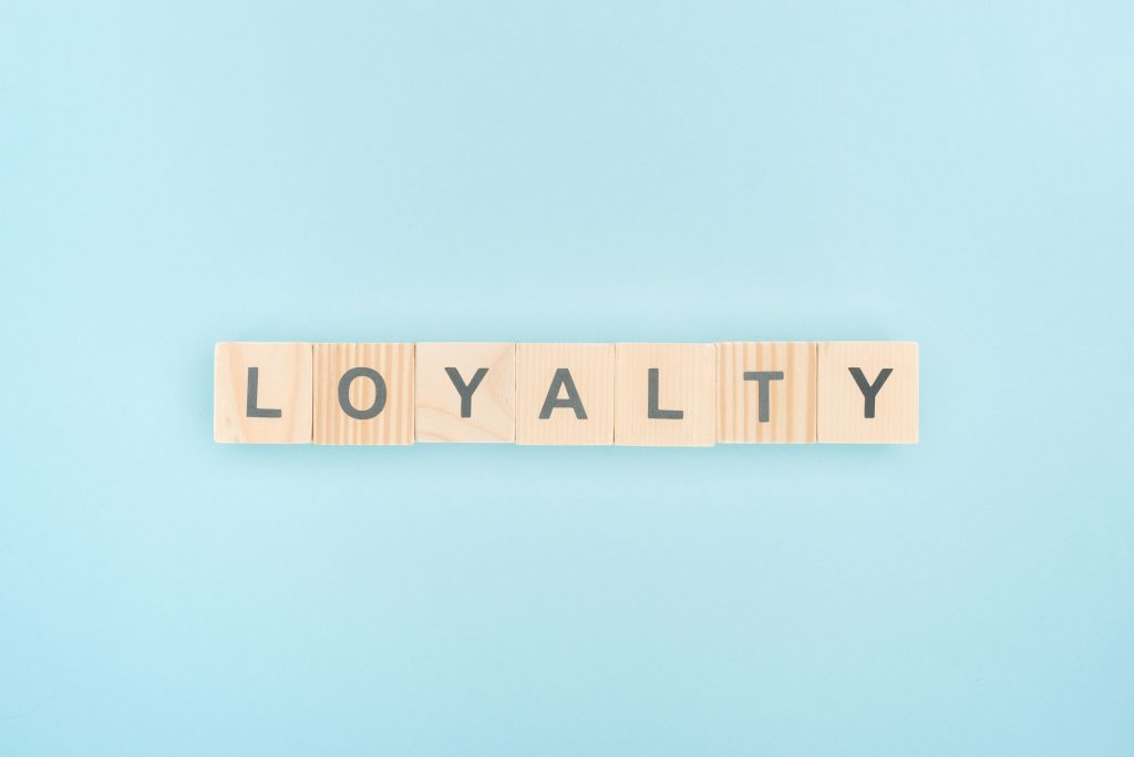 top view of loyalty lettering made of wooden cubes on blue background